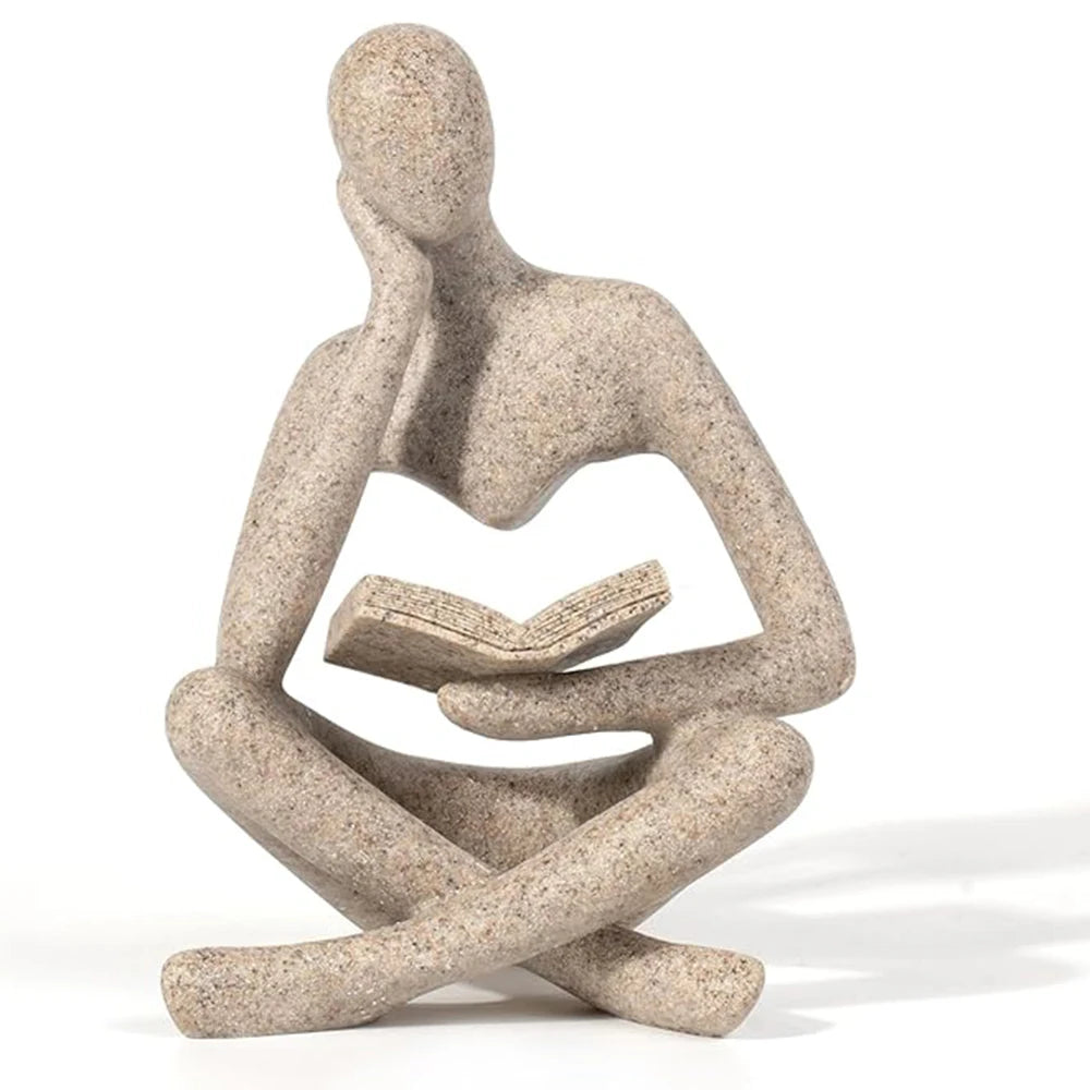 Stone sculpture of a person sitting with a book on a white background